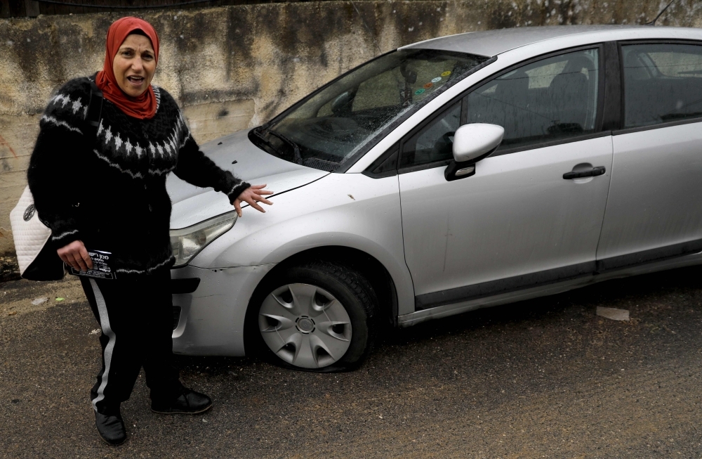 A Palestinian youth checks a car as vehicles with their tires slashed are pictured in the Palestinian neighborhood of Shuafat, neighboring the Israeli settlement of Ramat Shlomo, in Israeli annexed east Jerusalem, on Monday. — AFP