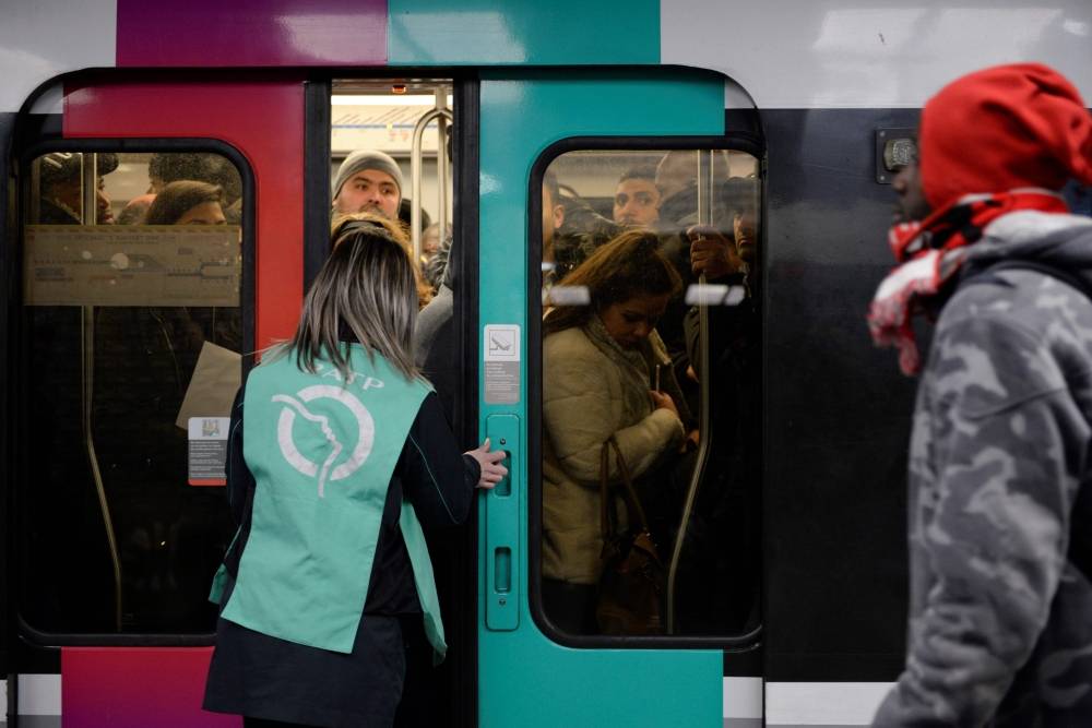 A Paris public transports operator RATP employee stands as commuters board on a RER B regional train at Chatelet-les Halles station in Paris on Monday during a strike of RATP employees over French government's plan to overhaul the country's retirement system, as part of a national strike. -AFP