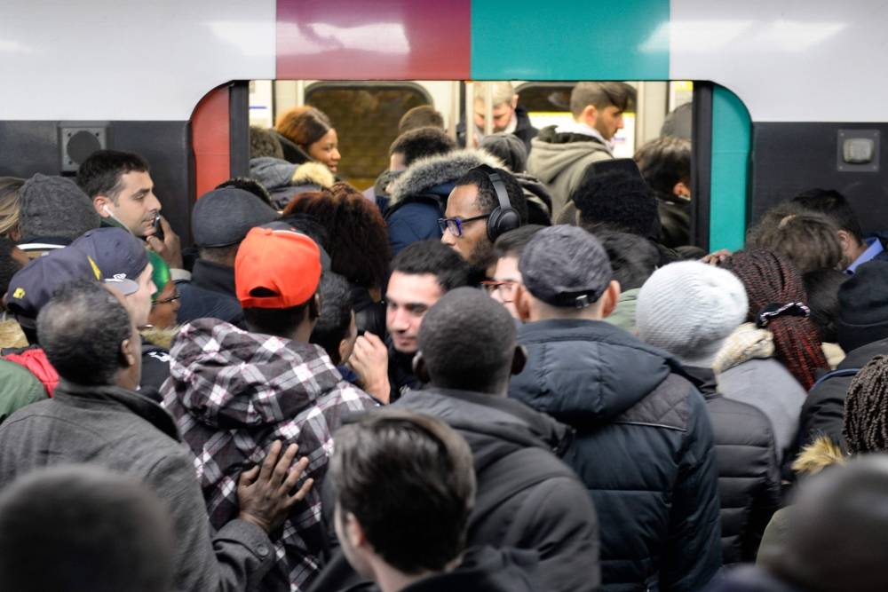 A Paris public transports operator RATP employee stands as commuters board on a RER B regional train at Chatelet-les Halles station in Paris on Monday during a strike of RATP employees over French government's plan to overhaul the country's retirement system, as part of a national strike. -AFP