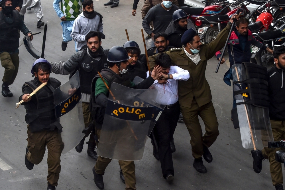 Policemen detain a lawyer, center in white shirt, following a clash between lawyers and doctors in Lahore, Pakistan, on Wednesday. — AFP
