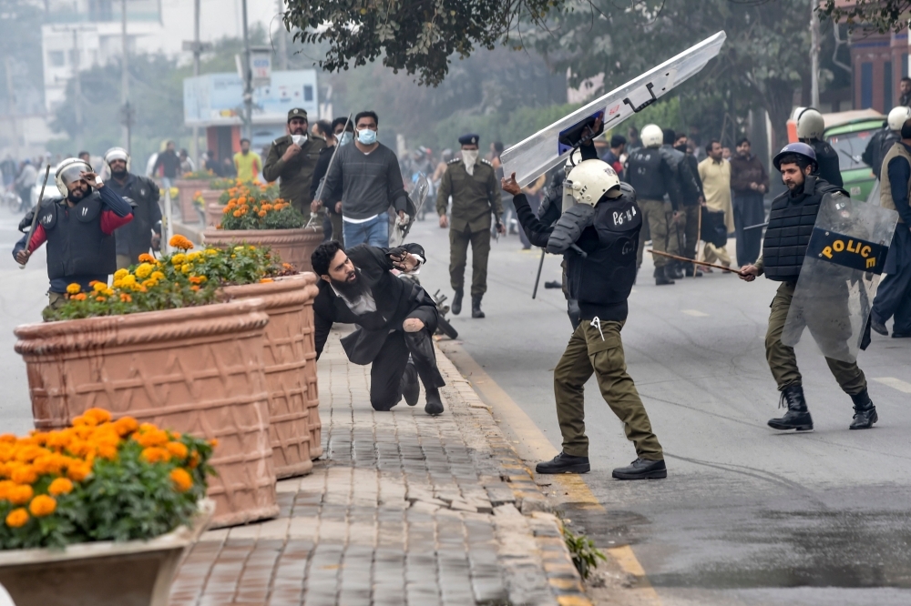 Policemen detain a lawyer, center in white shirt, following a clash between lawyers and doctors in Lahore, Pakistan, on Wednesday. — AFP