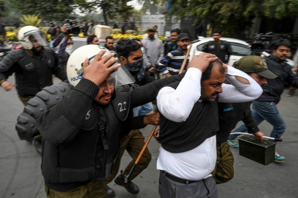 Policemen detain a lawyer, center in white shirt, following a clash between lawyers and doctors in Lahore, Pakistan, on Wednesday. — AFP