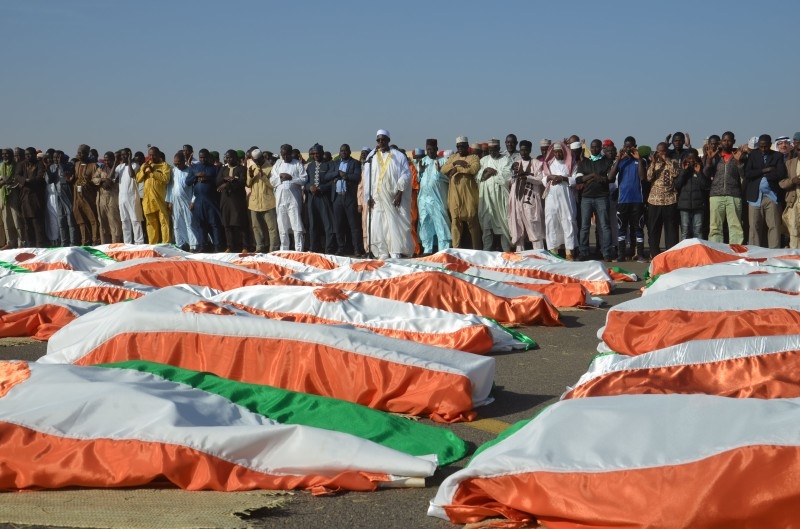 The Imam of the Great Mosque of Niamey, Cheikh Djabir Ismael, center, who led the funeral prayer, stands in front of the bodies of military personnel at the Niamey Airforce Base in Niamey, on Friday. — AFP