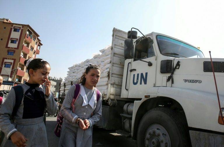 Palestinian schoolgirls walk past a United Nations aid truck transporting sacks of flour outside a UN compound in the southern Gaza Strip refugee camp of Rafah, on November 17, 2019 -AFP