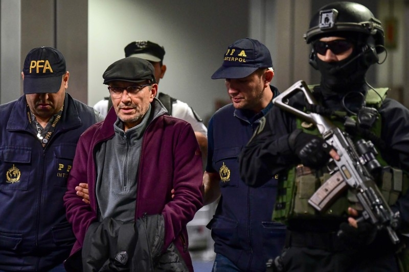 Argentine former police officer Mario Sandoval (2-L) is escorted by police officers upon his arrival at Ezeiza airport in Buenos Aires on Monday. -AFP