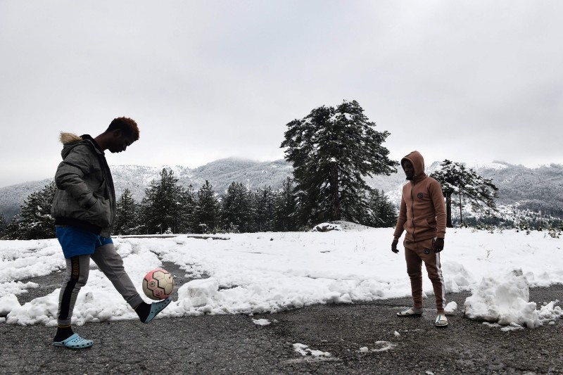 Two migrant men play football in the snow by a disused ski lodge near the village of Polineri, in Grevena, some 210km west of Thessaloniki, on December 12, 2019. -AFP