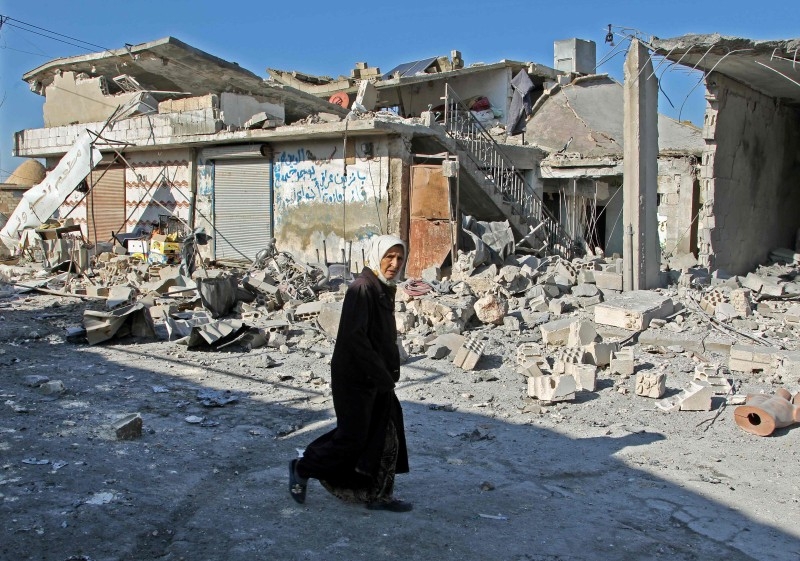 A Syrian woman walks past destruction at the site of a reported government bombardment in the village of Maasaran on the outskirts of Maaret Al-Numan in Syria's northwestern Idlib province on Tuesday. — AFP