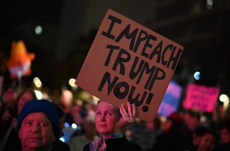 Protesters hold signs during a demonstration in part of a national impeachment rally, at the Federal Building in San Francisco, California on Tuesday. -AFP