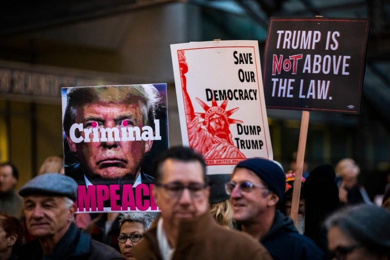 Protesters hold signs during a demonstration in part of a national impeachment rally, at the Federal Building in San Francisco, California on Tuesday. -AFP