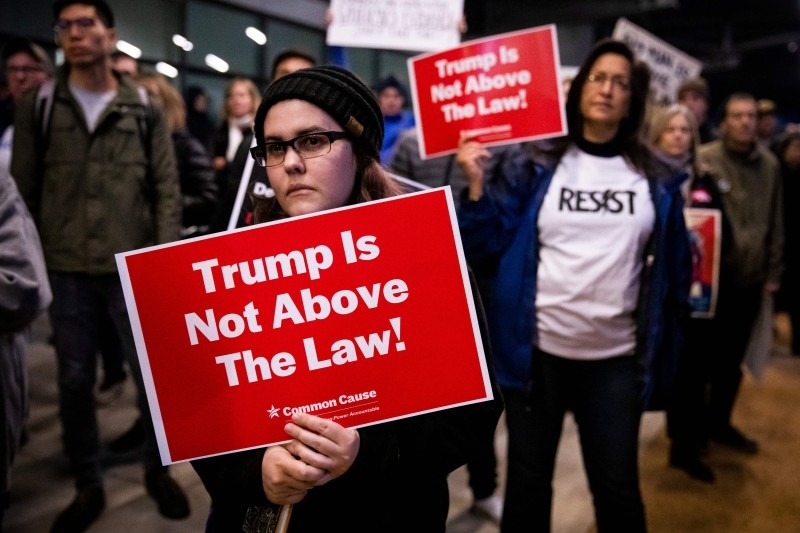 Protesters hold signs during a demonstration in part of a national impeachment rally, at the Federal Building in San Francisco, California on Tuesday. -AFP