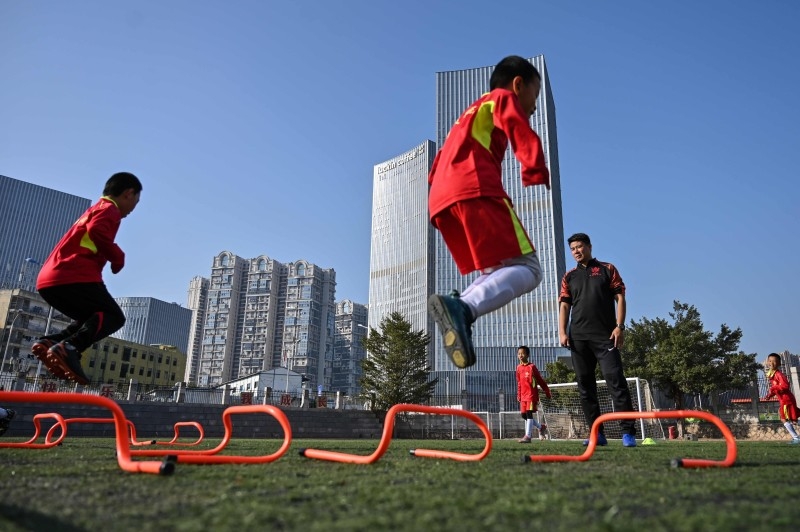 Former Manchester United and Chinese international footballer Dong Fangzhuo, right, watches as children train, in Xiamen in China's Fujian province, in this Dec. 10, 2019 file photo. — AFP