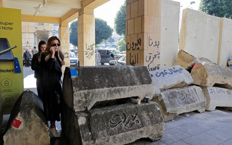 People walk through concrete barricades that were erected overnight to block or control access to protest sites, following attacks by counter-demonstrators, in the capital Beirut, on Wednesday. — AFP