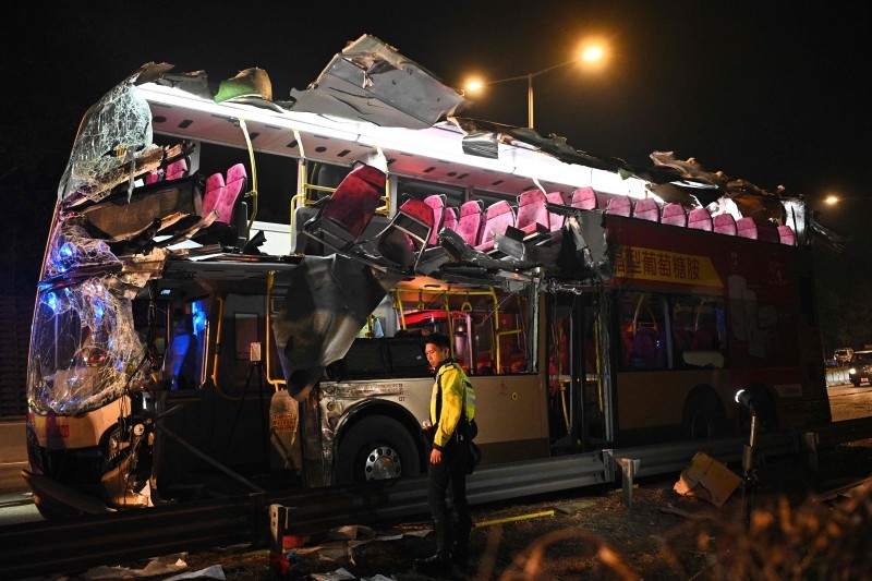 A police officer stands in front of a double-decker bus after a crash in Kwu Tung in Hong Kong on Wednesday. — AFP