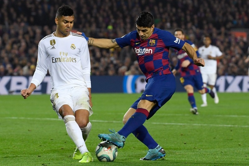 Real Madrid's Brazilian midfielder Casemiro, left, challenges Barcelona's Uruguayan forward Luis Suarez during the 