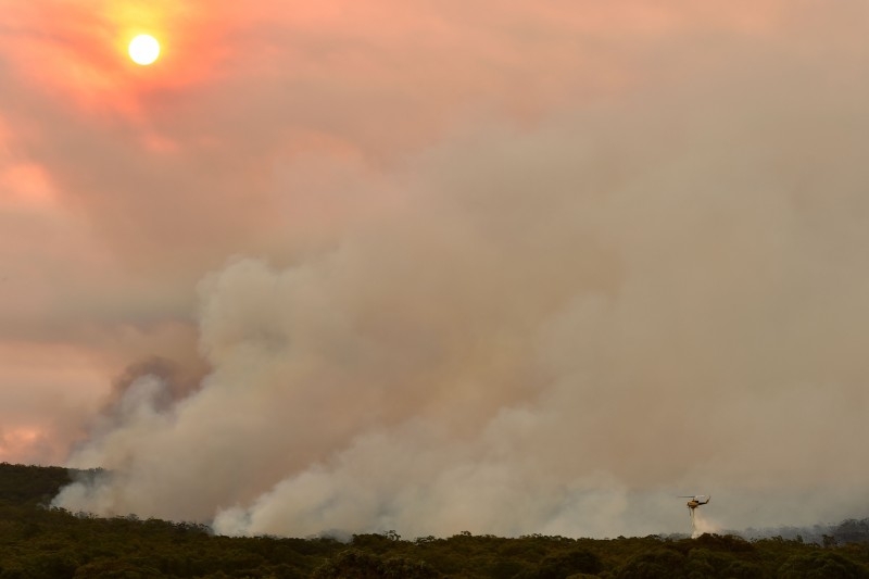 A helicopter drops water onto a large bushfire in Bargo, 150 km southwest of Sydney, on Thursday. — AFP