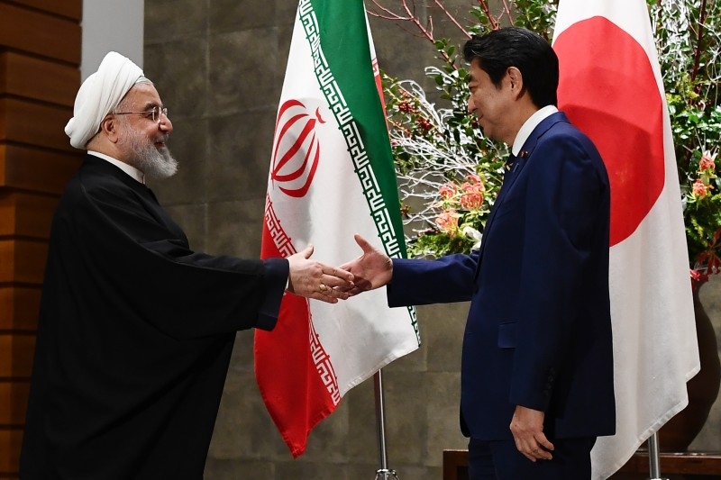 Iranian President Hassan Rohani, left, shakes hands with Japanese Prime Minister Shinzo Abe, right, before a meeting at the prime minister's office in Tokyo on Friday. — AFP