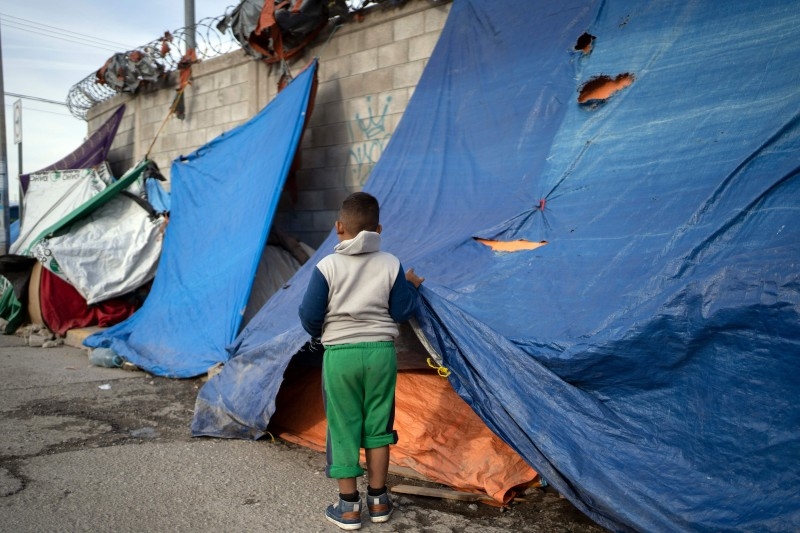 A man walks with his daughter at an asylum seekers camp near the Zaragoza bridge in Ciudad Juarez, Mexico, on December 11, 2019. -AFP