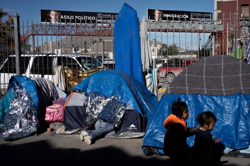 A man walks with his daughter at an asylum seekers camp near the Zaragoza bridge in Ciudad Juarez, Mexico, on December 11, 2019. -AFP