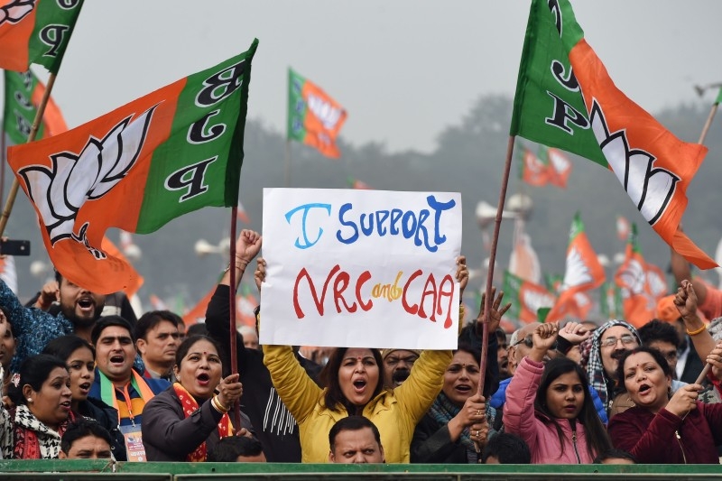 Supporters of the Bharatiya Janata Party (BJP) wave party flags and hold placards in support of the government's Citizenship Amendment Act (CAA) and the National Register of Citizens (NRC) during a rally in New Delhi on Sunday. -AFP