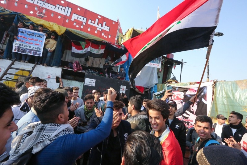 Iraqi anti-government protesters carry a large national flag during ongoing demonstrations in the capital Baghdad's Tahrir square, on Sunday. -AFP