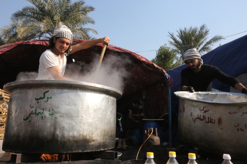 Iraqi men cook in large pots, meals for the demonstrators, in Baghdad's Tahrir square on Monday. — AFP