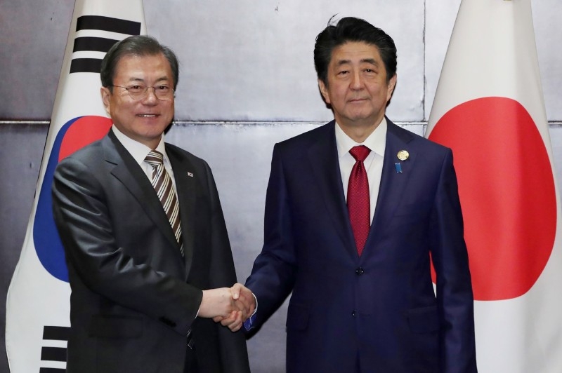 South Korea's President Moon Jae-in (L) shakes hands with Japan's Prime Minister Shinzo Abe during their meeting in Chengdu, southwestern China's Sichuan province on Tuesday. -AFP