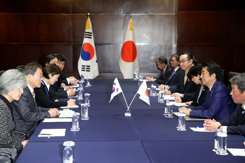 South Korea's President Moon Jae-in (L) shakes hands with Japan's Prime Minister Shinzo Abe during their meeting in Chengdu, southwestern China's Sichuan province on Tuesday. -AFP