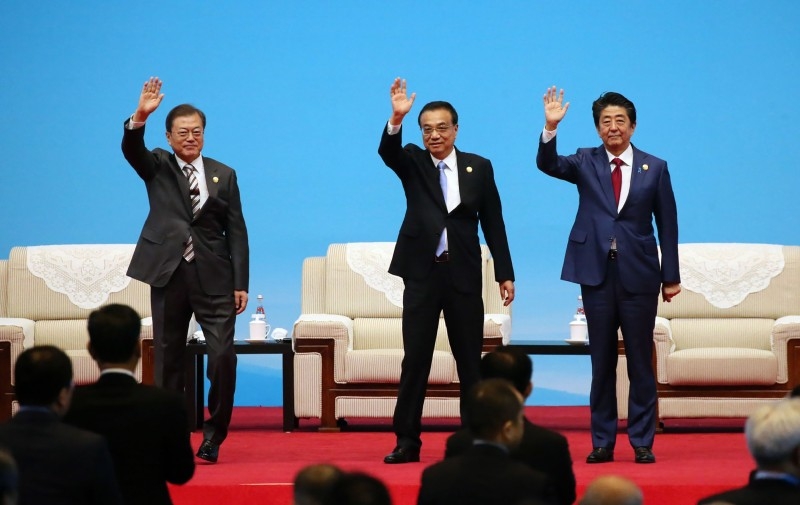 South Korea's President Moon Jae-in (L) shakes hands with Japan's Prime Minister Shinzo Abe during their meeting in Chengdu, southwestern China's Sichuan province on Tuesday. -AFP