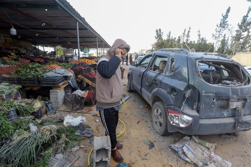 A man talks on his phone next to debris and damaged cars after a shell landed next to a vegetable store in the area of Bir Al-Osta Milad, in the Libyan town of Tajura, about 14 kilometers east of the capital Tripoli, on Tuesday. -AFP
 / AFP / Mahmud TURKIA