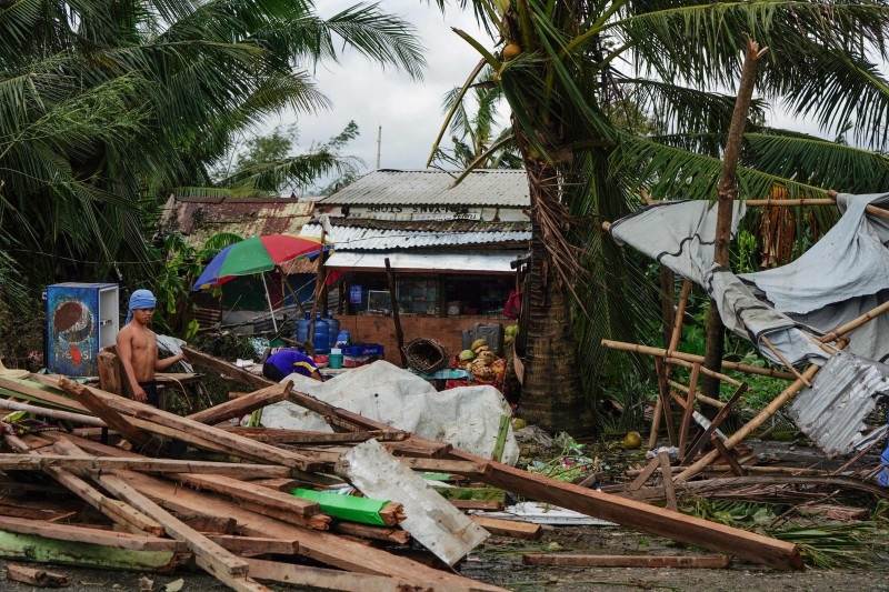 A motorist commutes past a blown down galvanised roof from a house damaged during the height of Typhoon Phanfone in Tacloban, Leyte province in the central Philippines on Wednesday. -AFP