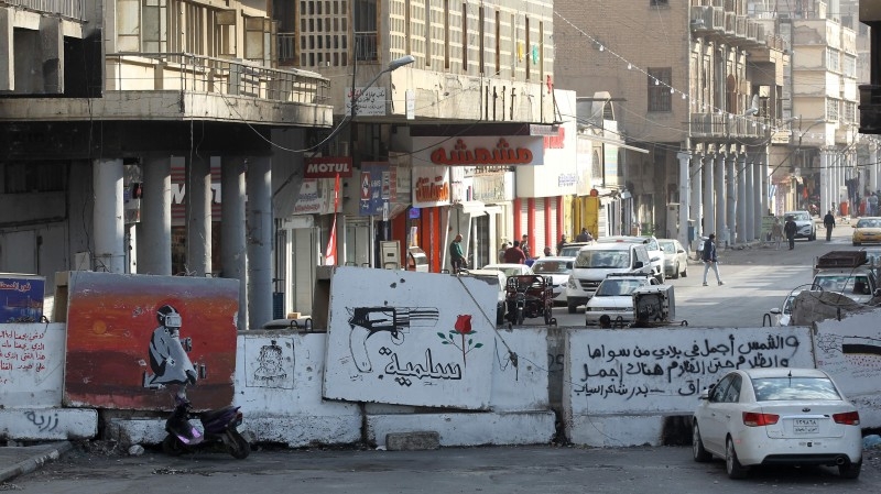 A cameraman films an actress performing a scene as she reacts while holding up a red-stained Iraqi national flag, in Rasheed street in the capital Baghdad, on Wednesday. — AFP