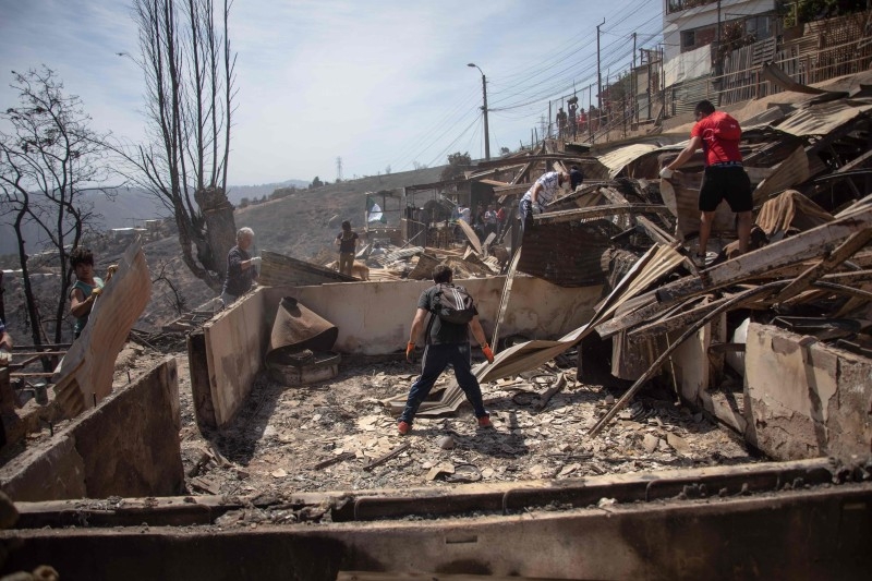 Locals search for personal belongings after a forest fire at the Rocuant hill in Valparaiso, Chile, on Wednesday. — AFP