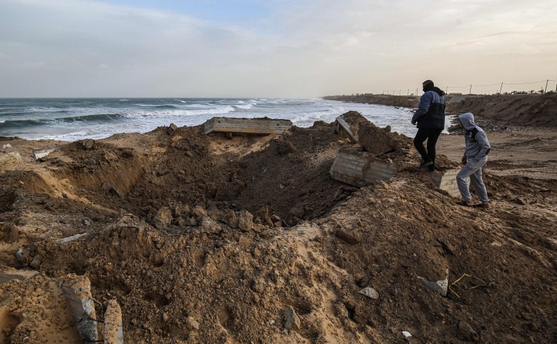 Palestinians check an impact crater at the site of an Israeli air strike in Khan Yunis in the southern Gaza Strip on Thursday. — AFP
