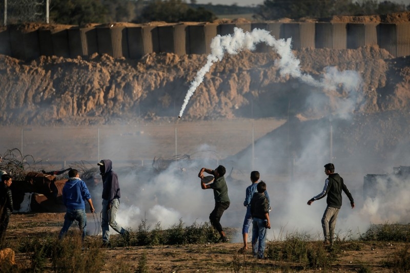 A Palestinian protester throws back a tear gas canister at Israeli forces amid clashes following a demonstration along the border with Israel east of Bureij in the central Gaza Strip in this Dec. 20, 2019 file photo. — AFP