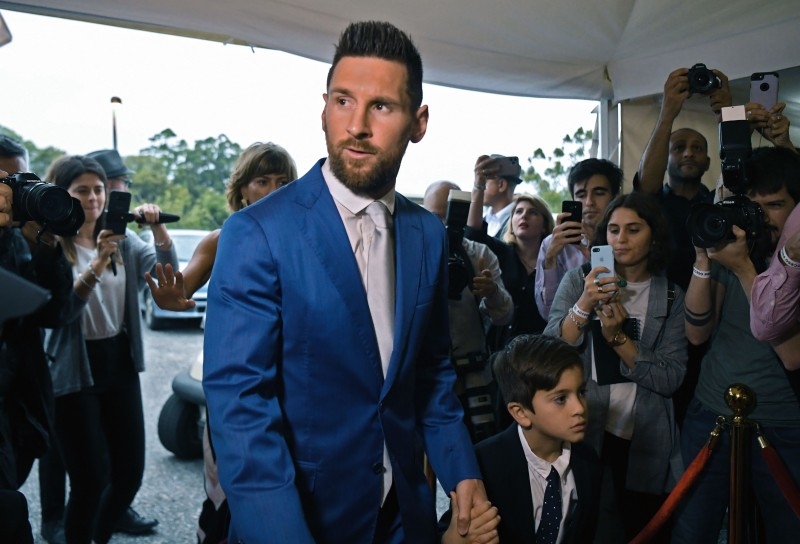 Argentinian Bolcelona forward Lionel Messi arrives with his son Thiago (C-R) at a party thrown by Uruguayan Barcelona forward Luis Suarez for the renewal of his marriage vows in La Barra, near Punta del Este, Uruguay, on Thursday — AFP