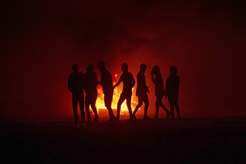 Iraqi anti-government protesters stand next to a burning roadblock in the southern city of Basra late on Thursday. — AFP