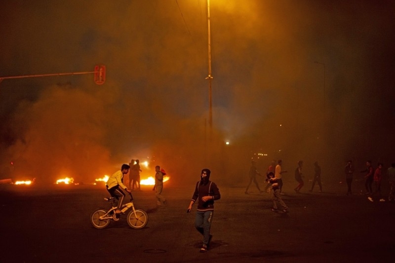 Iraqi anti-government protesters stand next to a burning roadblock in the southern city of Basra late on Thursday. — AFP