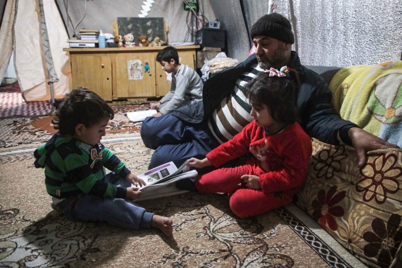 Hussein Berro, a 51-year-old displaced Syrian, sits with his children inside their tent at a camp in Khirbet Al-Joz in the west of the northwestern Idlib province near the border with Turkey, in this Dec. 12, 2019 file photo. — AFP