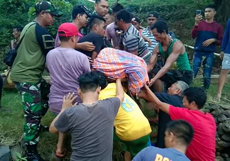 This handout picture taken and released on Thursday by Kendari Search and Rescue Agency shows villagers and a rescue team moving a victim's body after being killed by a crocodile near Bendewuta village, North Konawe, in Indonesia's Southeast Sulawesi. — AFP