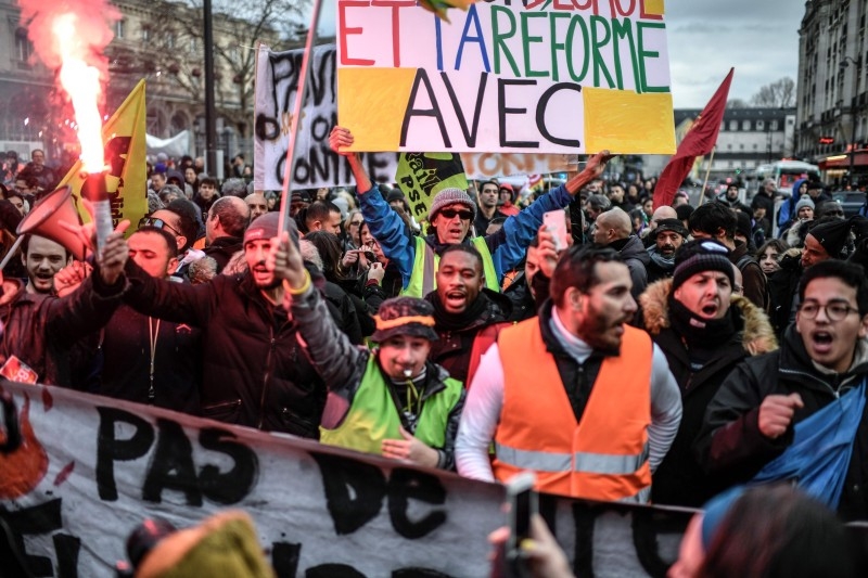 French activist Jean-Baptiste Redde aka Voltuan, center, holds a placard as he takes part in a demonstration of rail workers and employees of Paris' RATP public transport operator near the Gare de l'Est railway station in Paris on Thursday, as part of a nationwide multi-sector strike against French government's pensions overhaul. — AFP