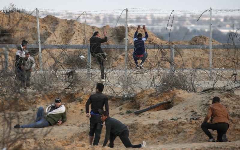 A Palestinian protester uses a sling to hurl stones at Israeli troops at the Israel-Gaza border fence, east of Rafah in the southern Gaza Strip, on Friday. — AFP