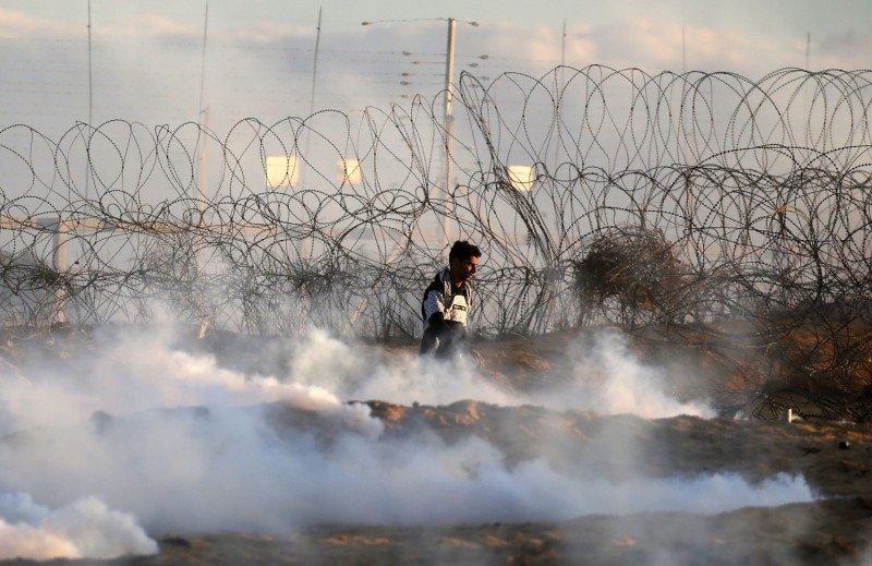 A Palestinian protester uses a sling to hurl stones at Israeli troops at the Israel-Gaza border fence, east of Rafah in the southern Gaza Strip, on Friday. — AFP