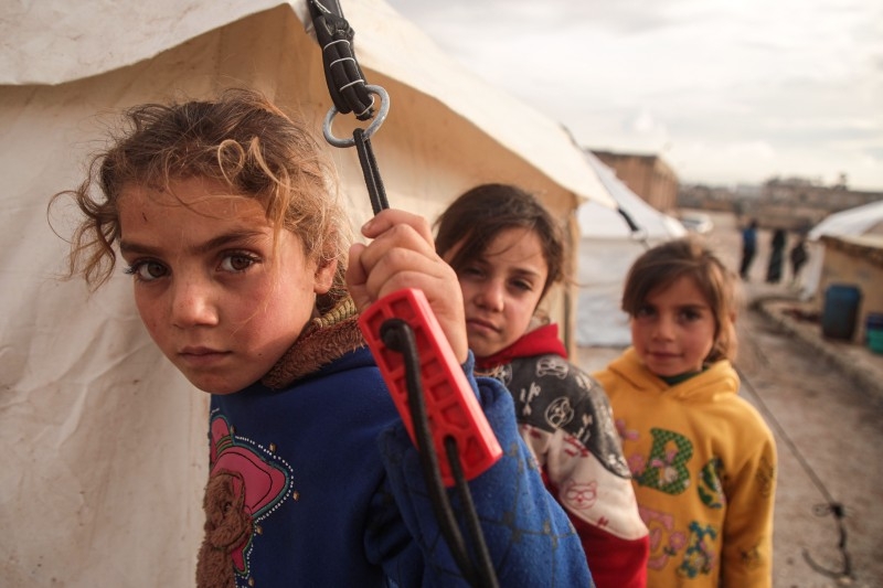 Syrian children, among those who fled from government forces' advance on Maaret Al-Numan in the south of Idlib prvoince, look on as they stand outside tents at a camp for the displaced near the town of Dana in the province's north near the border with Turkey, on Friday. — AFP