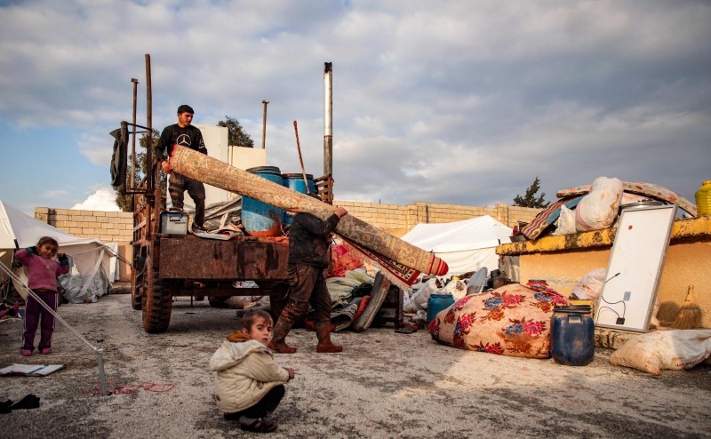 Syrian children, among those who fled from government forces' advance on Maaret Al-Numan in the south of Idlib prvoince, look on as they stand outside tents at a camp for the displaced near the town of Dana in the province's north near the border with Turkey, on Friday. — AFP