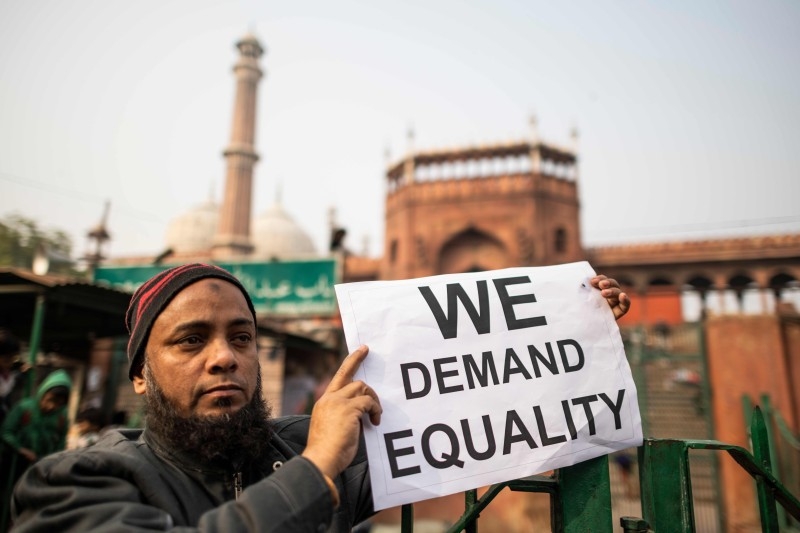 TOPSHOT - A protester displays a placard during a demonstration against India's new citizenship law outside the Jama Masjid mosque in New Delhi on Friday. -AFP