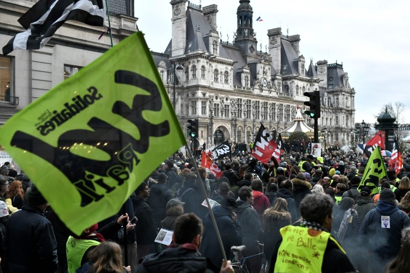 Protesters demonstrate as part of a nationwide multi-sector strike against French government's pensions overhaul near the city hall in Paris on Saturday. -AFP