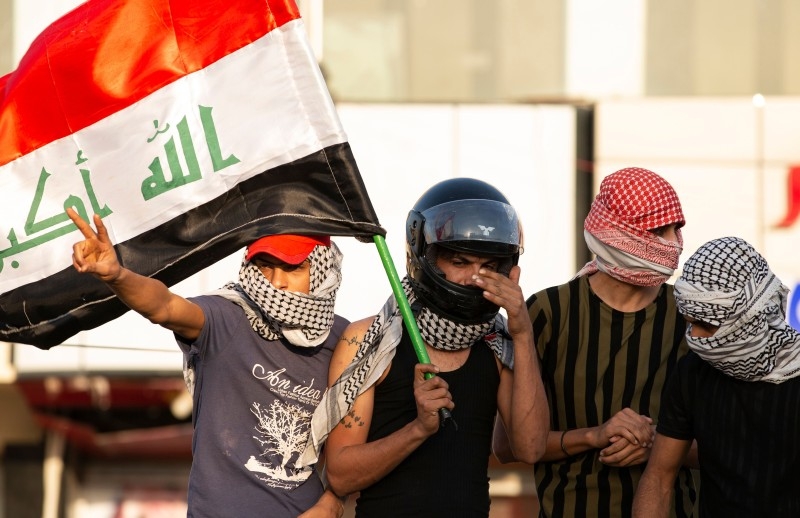 Iraqis wave the national flag in the southern city of Basra on Monday, during a demonstration to denounce the previous night's attacks by US planes on several bases belonging to the Hezbollah brigades near Al-Qaim, an Iraqi district bordering Syria. — AFP