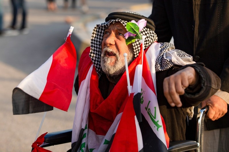 Iraqis wave Hashed Al-shaabi armed network flags in the southern city of Basra on Monday, during a demonstration to denounce the previous night's attacks by US planes on several bases belonging to the Hezbollah brigades near Al-Qaim, an Iraqi district bordering Syria.   -AFP