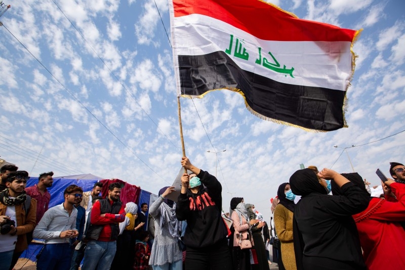 An Iraqi student waves the national flag during an anti-government demonstration in the southern city of Basra on Tuesday. -AFP