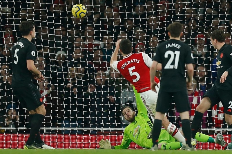 Arsenal's Greek defender Sokratis Papastathopoulos (C) shoots past Manchester United's Spanish goalkeeper David de Gea to score their second goal during the English Premier League football match at the Emirates Stadium in London on Wednesday. — AFP